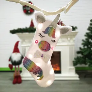 LED unicorn Christmas stocking in white faux fur hanging on branches for festive decor