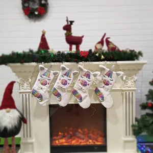 Set of 4 white plush unicorn Christmas stockings with rainbow accents on a festive mantel