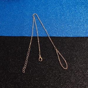 Détail de la chaîne à billes dorée avec fermoir mousqueton et extension sur fond scintillant