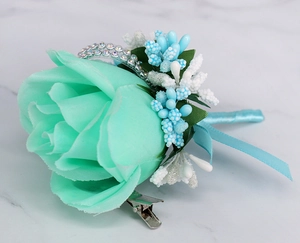 Detailed view of mint green silk rose boutonniere with blue berries and rhinestones
