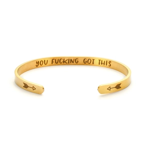 Macro detail of gold plated cuff bracelet showing the YOU FUCKING GOT THIS engraving
