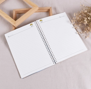 Detail of metal spiral notebook with ruled pages and decorative dried flowers background