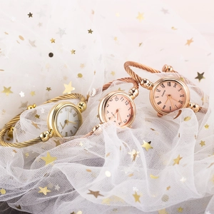 Detailed display of three quartz bangle watches in gold and rose gold on a sequined tulle