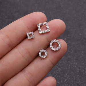 Set of four silver geometric stud earrings with sparkling cubic zirconia on dark background