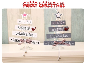 Close-up of wooden Christmas tree hanging sign with text and metal bells ornament