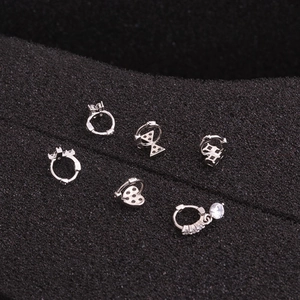 Macro shot of silver cartilage earrings set with zircon heart and geometric shapes