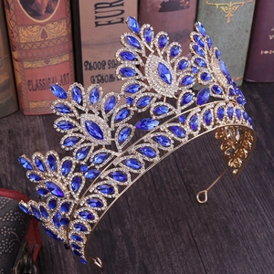 Dettaglio di corona nuziale barocca dorata con strass blu su libri in stile vintage