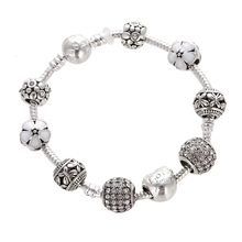 Close-up of silver snake chain bracelet with colorful unicorn and heart charms