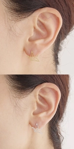 Dettaglio degli orecchini a perno a gru origami in oro e argento sul lobo