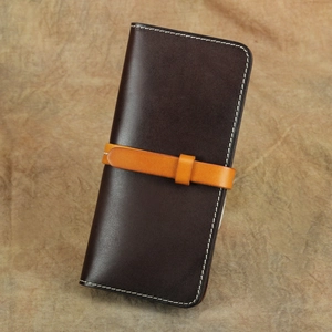 Dettaglio portafoglio vintage in pelle marrone con cinturino arancione e cuciture bianche