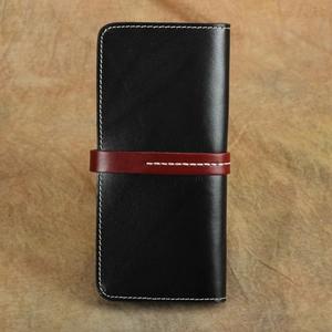 Dettaglio portafoglio vintage in pelle nera con cinturino rosso e cuciture bianche