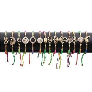 Detailed close-up of 14 colorful woven bracelets with gold-plated zircon charms on display