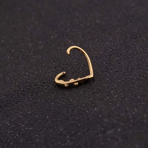 Macro view of gold ear cuff with three decorative beads on a dark matte surface