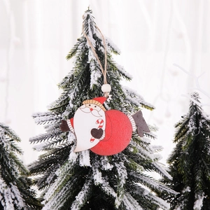 Handcrafted wooden Santa Claus ornament hanging on a snow-covered Christmas tree branch