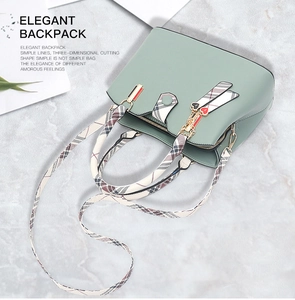 Mint green textured handbag with plaid shoulder strap and heart charm on marble surface