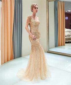 Dettaglio dell'abito dorato con paillettes, spalle con frange e fondo a sirena