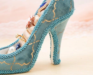 Close-up of light blue high heel ring holder with gold embroidery and lace trim detail