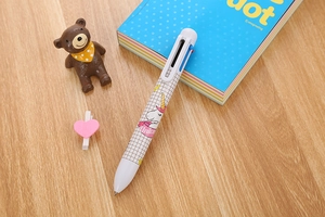 Detail of multi-color unicorn ballpoint pen on desk with cute stationery accessories