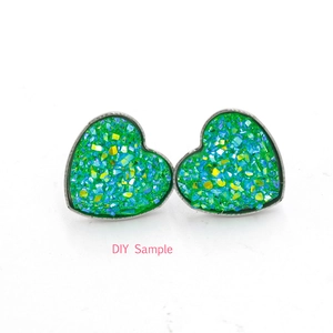 Detailed view of silver heart stud earrings with sparkling green druzy stone inlay