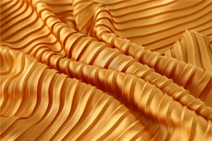 Macro detail of golden pleated satin scarf fabric with wavy texture and silk gloss