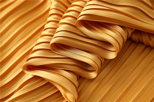 Macro detail of golden pleated satin scarf fabric with elegant metallic luster texture