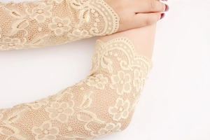 Detail of elegant beige lace arm sleeves featuring floral mesh and scalloped edges