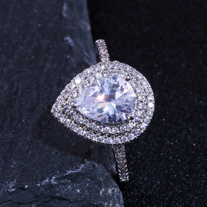 Macro shot of silver pear-shaped halo ring with double pave setting on rock background