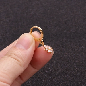 Macro shot of gold leaf pendant earring with zircon stones held by fingers