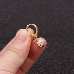 Detailed close-up of a golden sunflower earring with sparkling zircon petals held by hand