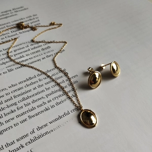 Macro shot of minimalist gold polished necklace and stud earrings set on magazine