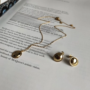 Polished gold jewelry set with necklace and earrings displayed on a fashion book
