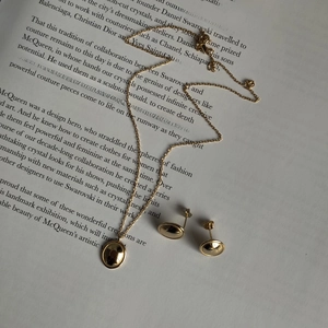 Detailed view of 925 silver gold jewelry set with oval charms on a fashion book background