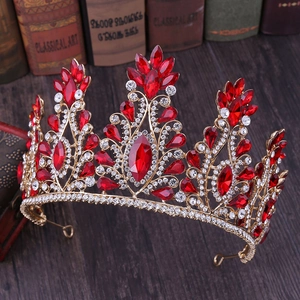 Close-up of golden bridal crown with red teardrop crystals on a dark wood surface