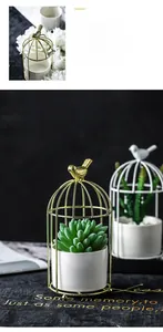 Detail of a birdcage-shaped gold metal frame with white ceramic succulent planter