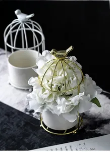 Macro detail of golden birdcage metal frame with decorative bird on a ceramic base