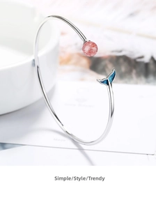Close-up of strawberry crystal bead and blue enamel fish tail on silver bangle