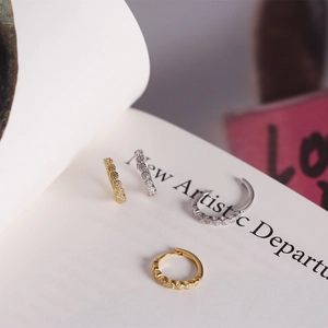 Detailed view of silver and gold mini hoop earrings with cubic zirconia on a book page