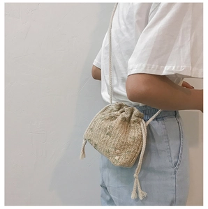 Detail of woven straw bucket bag with floral embroidery and drawstring closure