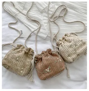 Detailed view of three woven bucket bags with floral embroidery and drawstring closure