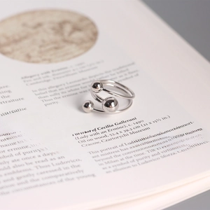 Close-up of minimalist silver beaded wrap ring placed on an open book page