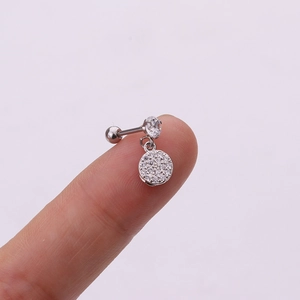 Macro view of crystal paved round pendant surgical steel cartilage stud on a finger