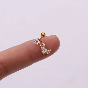 Macro detail of a gold moon cartilage piercing with zircons shown on a fingertip