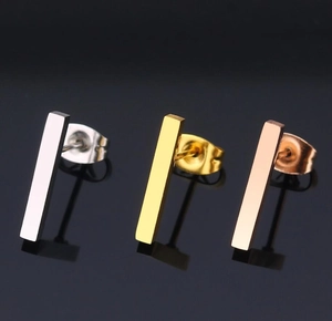 Macro shot of minimalist geometric rectangular stud earrings in silver, gold, and rose gold