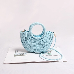 Detail view of light blue straw handbag with crescent shape and woven texture