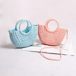 Detail of mini woven straw handbags in pink and blue with integrated round handles
