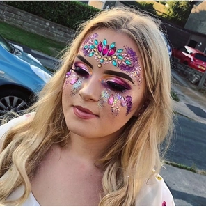 Close-up of a model wearing colorful rhinestone face jewels and purple glitter for masquerade