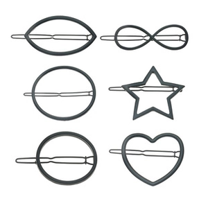 Close-up of six dark gray metal geometric hair clips including star and heart shapes