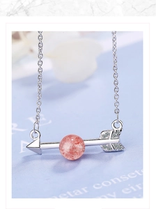 Macro shot of silver arrow pendant with pink moonstone bead and sparkling white crystals