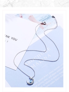 Detail of S925 sterling silver moon pendant necklace with blue teardrop gemstone