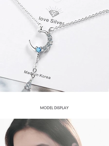 Macro detail of crescent moon necklace with blue zircon and teardrop crystal pendant